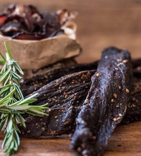 Beef jerky with rosemary on a wooden surface