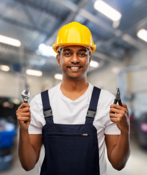 Mechanic in hard hat holding wrench and pliers to perform maintenance services