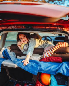 Child with colorful socks lying in a packed car trunk